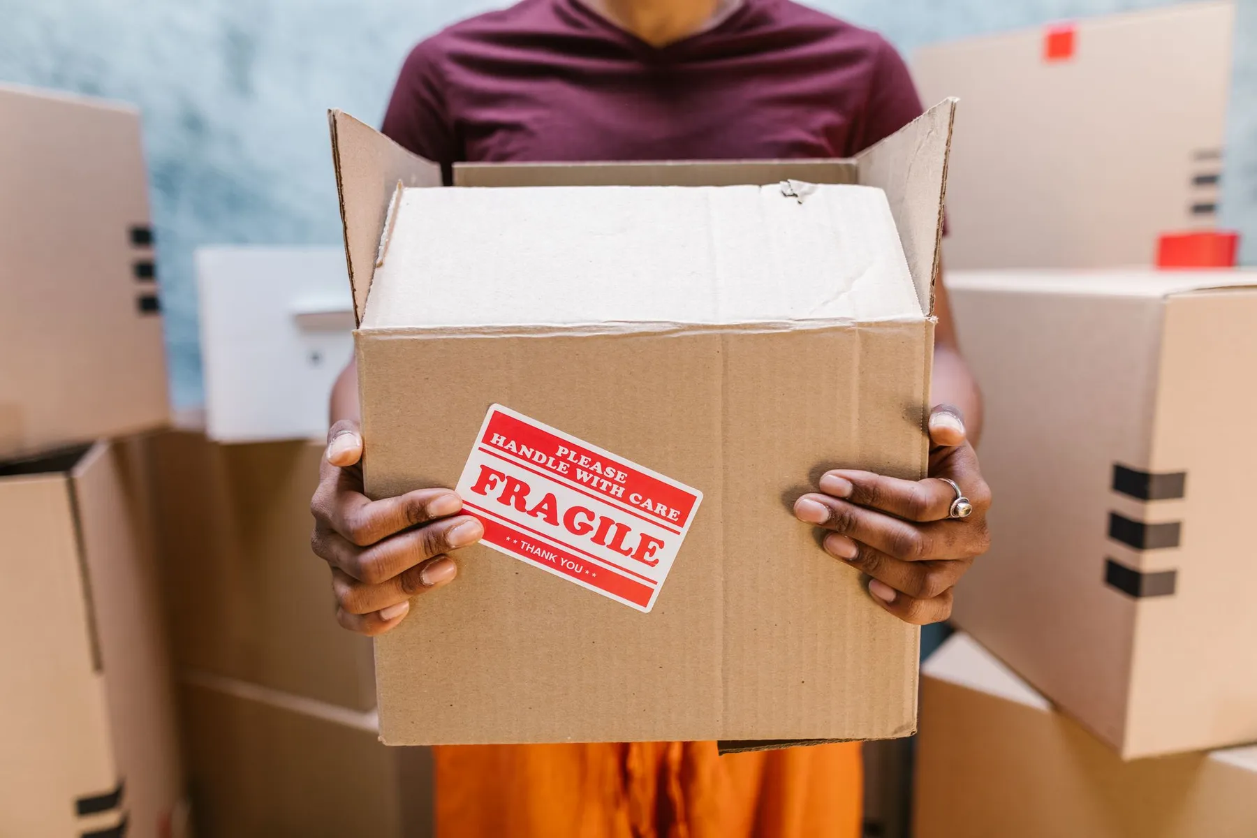Hands holding a cardboard box with a Fragile handle-with-care label
