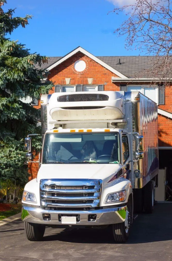 White Granero Moving box truck parked in front of a brick house